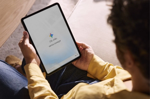 Visão superior de um homem segurando um tablet com Gemini aberto.