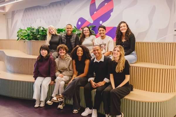 Grupo de 10 jovens sentados, sorrindo e posando para câmera.
